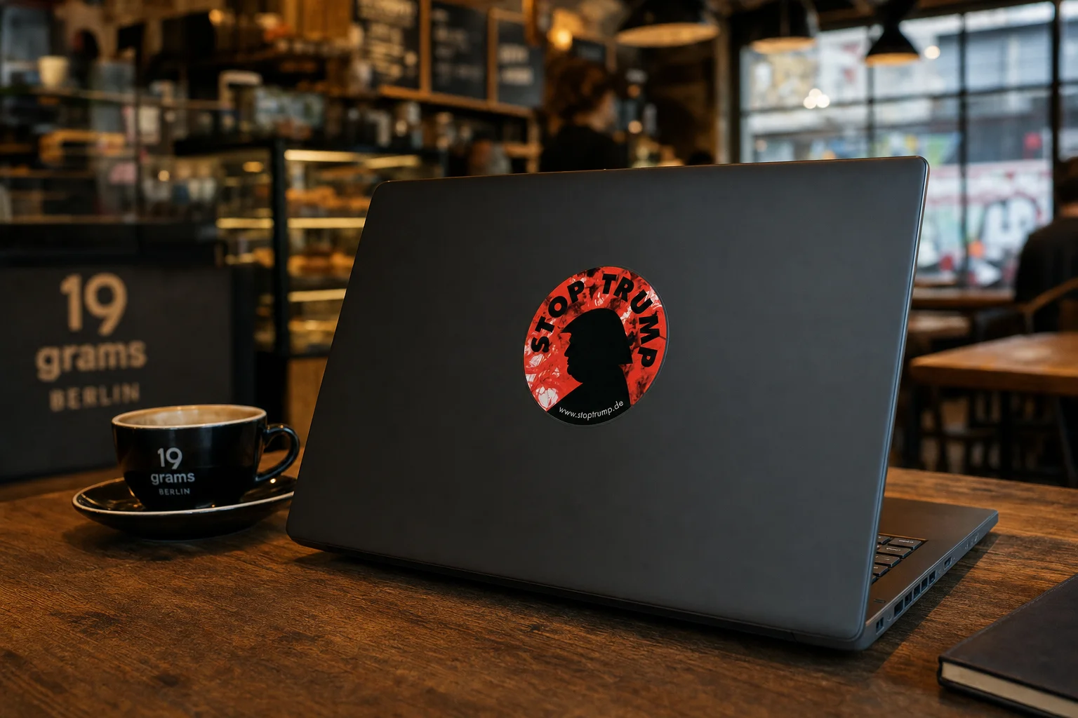 StopTrump Sticker auf Laptop im Café